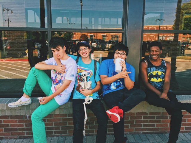 Four teenage boys sitting together on a brick ledge